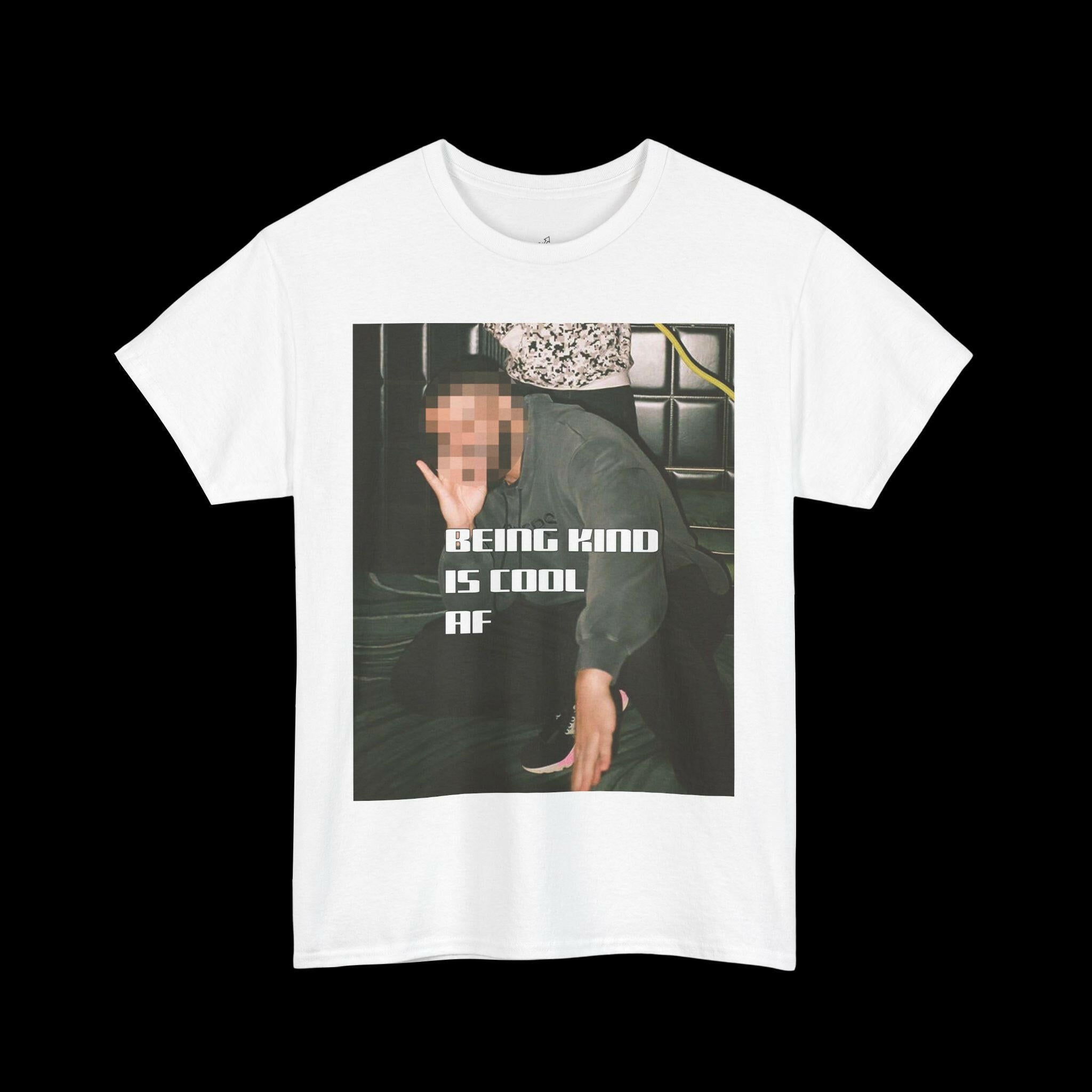 White "BEING KIND IS COOL AF" t-shirt with a graphic of a person, showcasing a positive and cool message. Ideal for unisex casual wear.