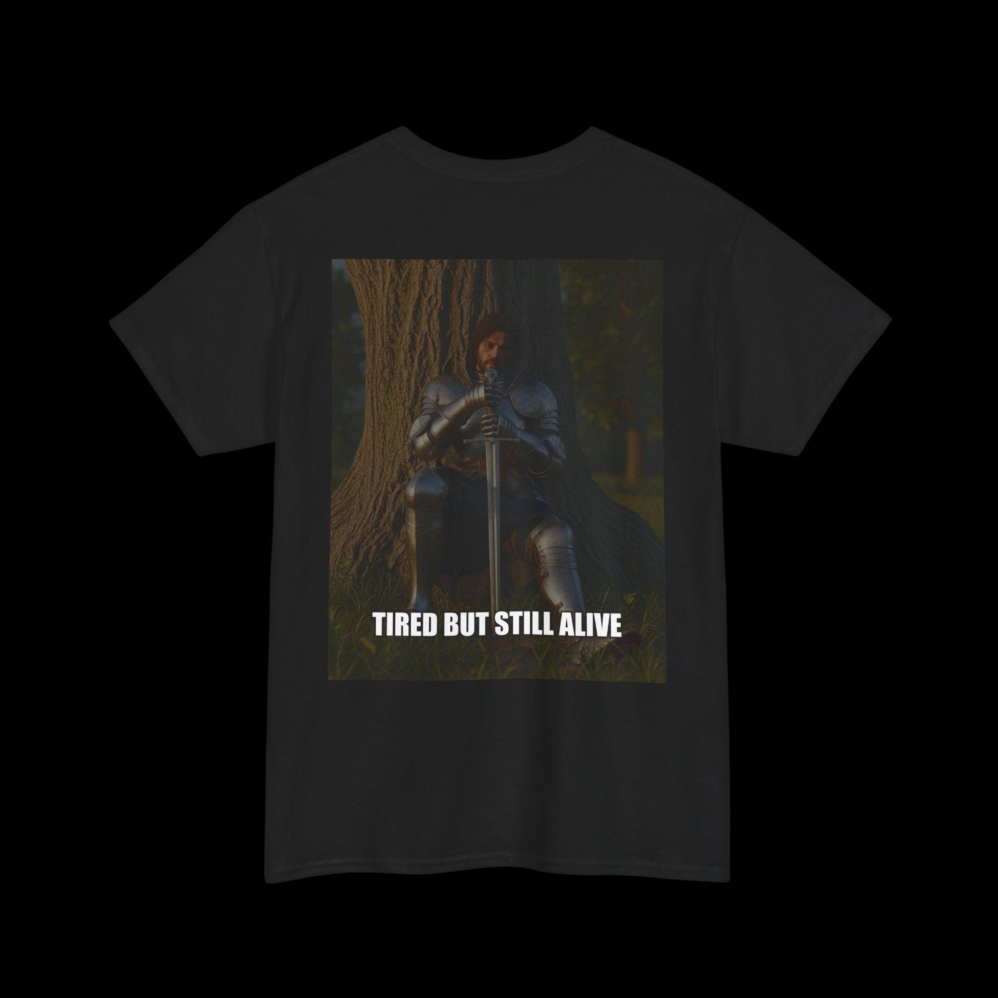 Black t-shirt featuring a graphic of a tired but resolute knight in armor sitting with a sword, and the text "TIRED BUT STILL ALIVE". Ideal for expressing strength and perseverance in a dark aesthetic.